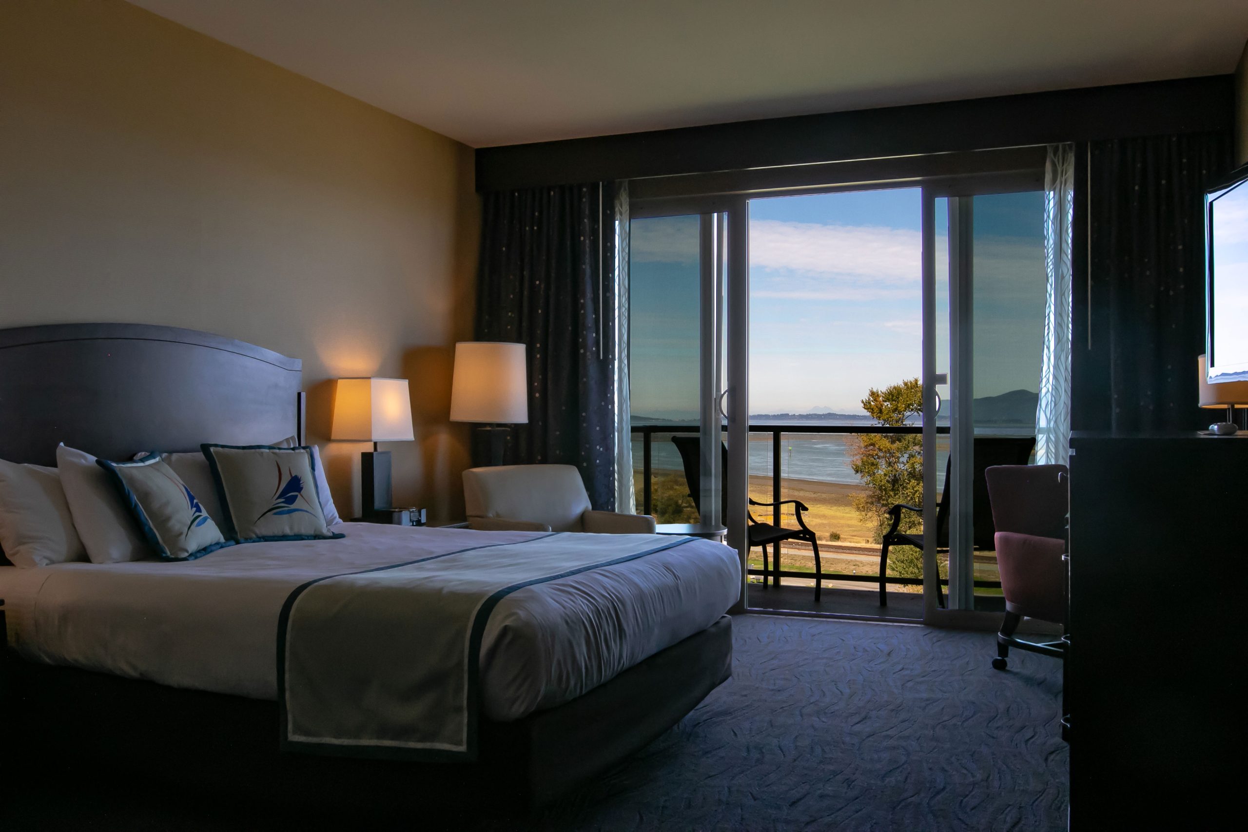 Deluxe Bay View room shows two queen beds, dresser, TV, work station and a bay view.